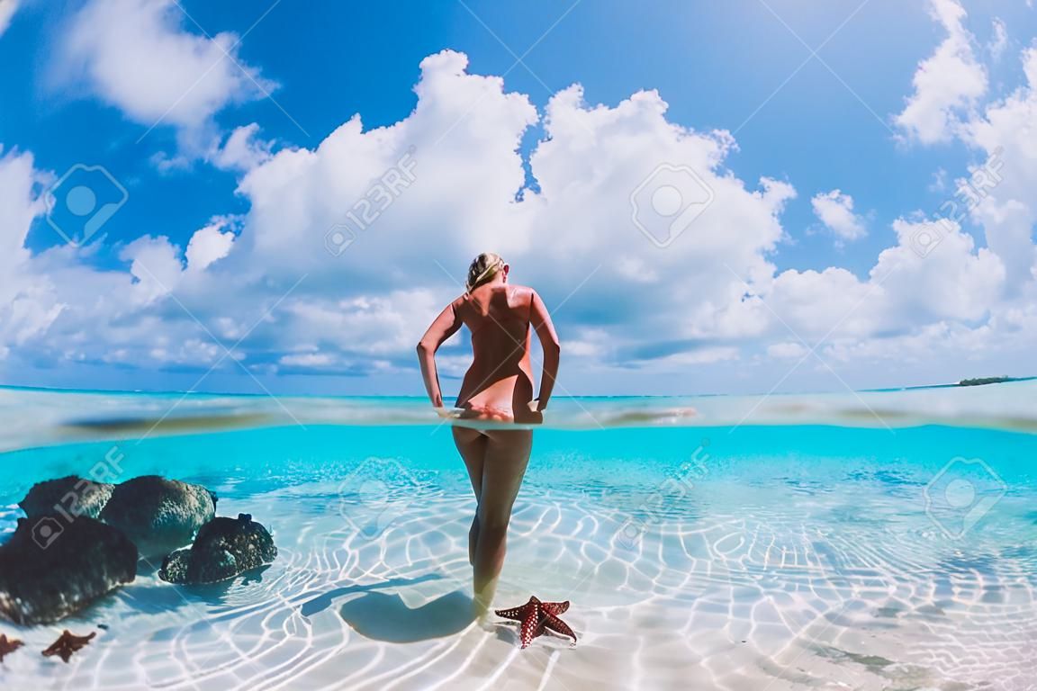 Beautiful woman posing in tropical sea with starfish, Bahamas islands