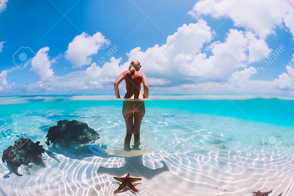 Piękna kobieta pozuje w tropikalnym morzu z rozgwiazdami, wyspy bahamy
