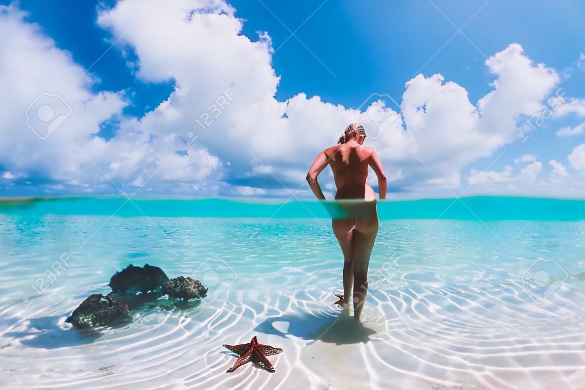 Schöne Frau posiert im tropischen Meer mit Seesternen, Bahamas-Inseln