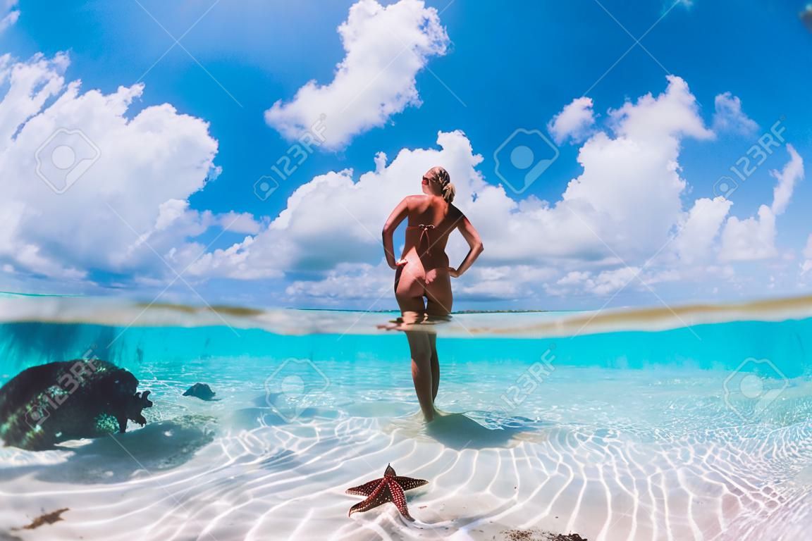 Hermosa mujer posando en el mar tropical con estrellas de mar, Islas Bahamas