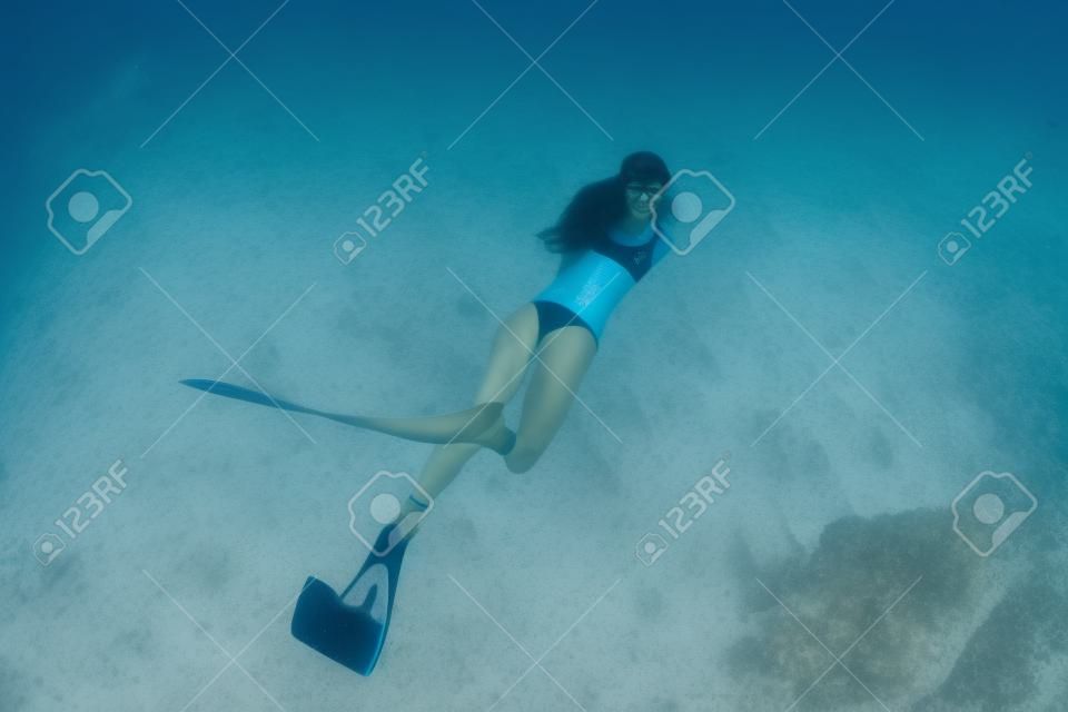 Mujer freediver posando en el mar de arena con aletas. Buceo libre en Bahamas