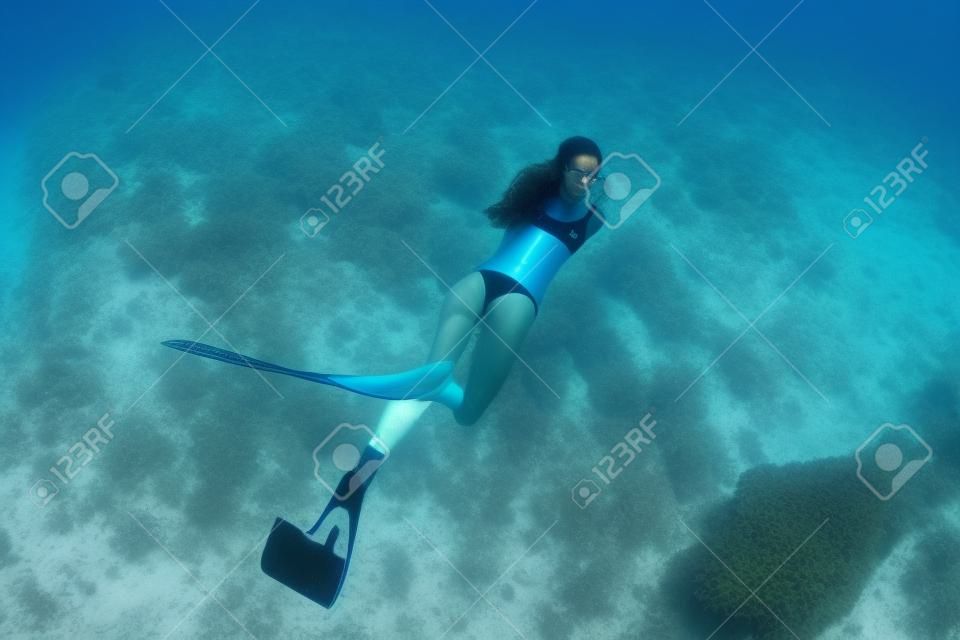 Freitaucherin posiert auf sandigem Meer mit Flossen. Freitauchen auf den Bahamas