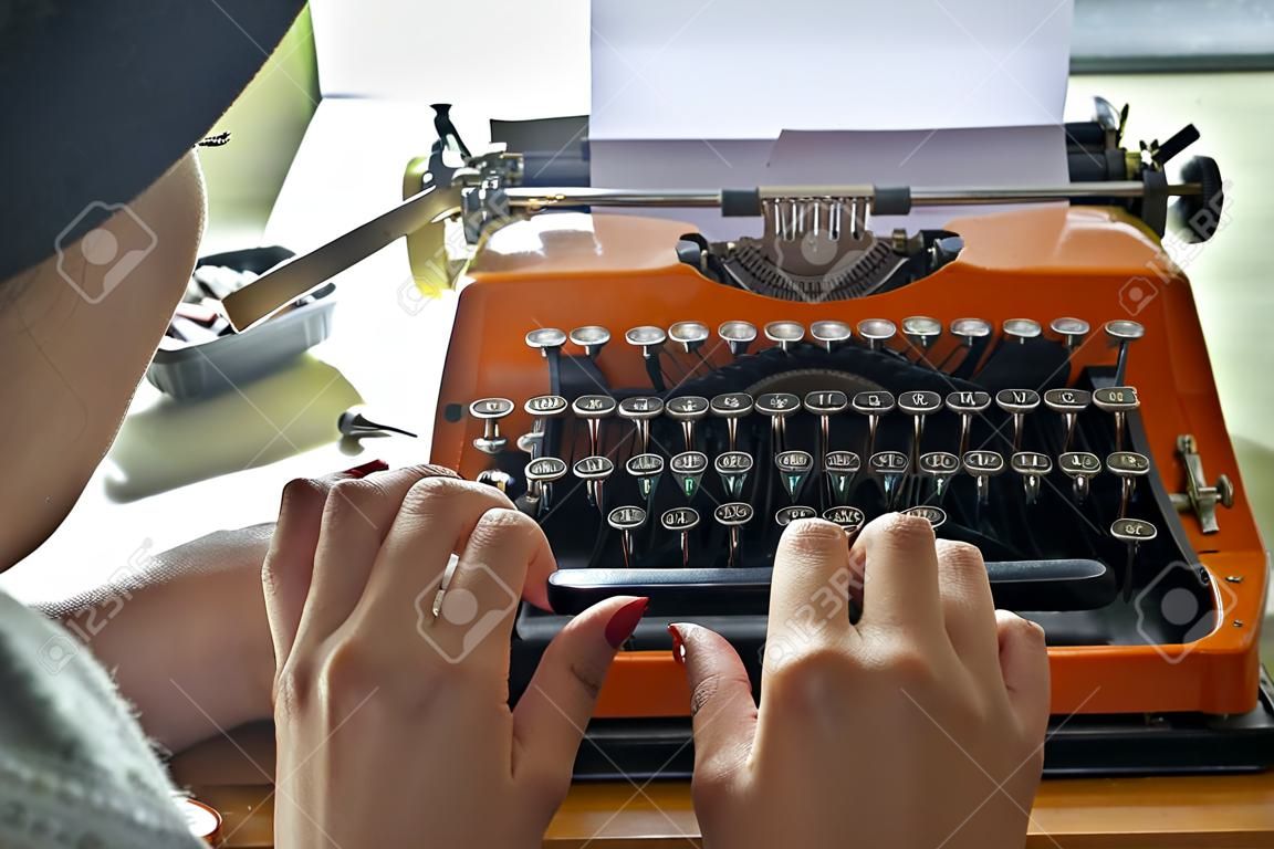 Frau schreibt auf einer alten Schreibmaschine.