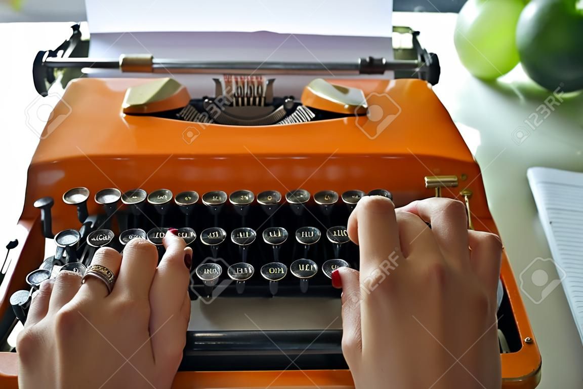 Frau schreibt auf einer alten Schreibmaschine.