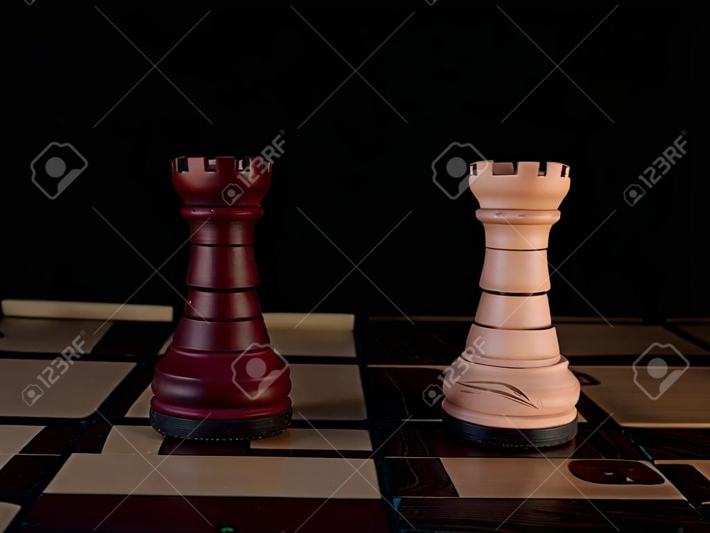 Twee met de hand versierde, houten schaaktorens staan op een schaakbord.