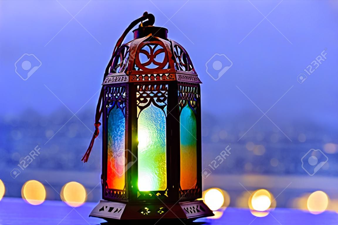 Lantaarn met lichten versieren voor islamitische nieuwjaar geplaatst op het raam met wazige blauwe achtergrond.