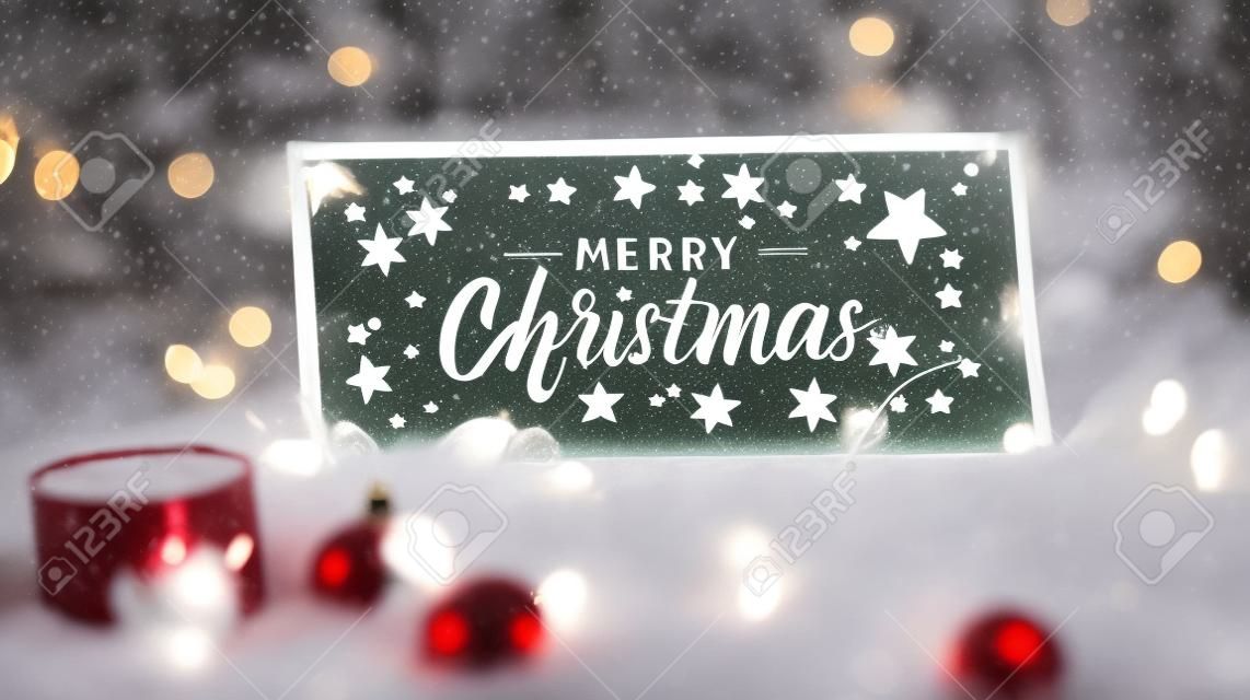 Merry Christmas lettering on a glass sign or tray on a white fur along with Christmas decorations and lights