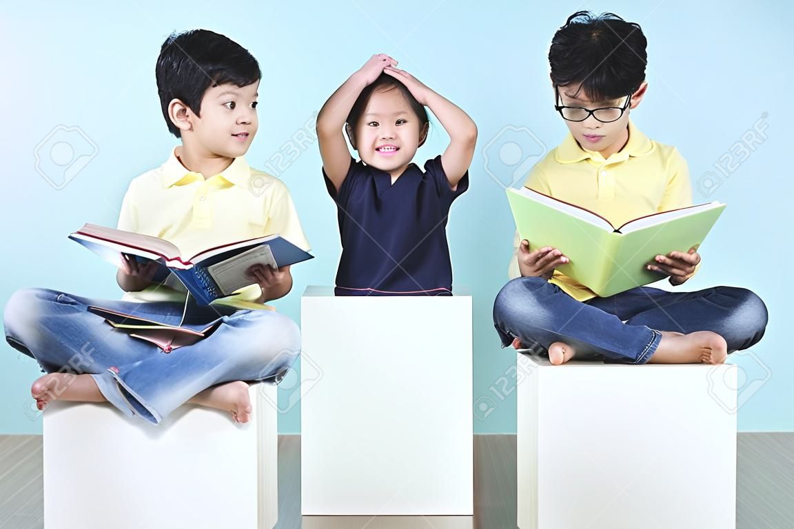 Asya sevimli çocuklar sandalye üzerinde kitap okuma