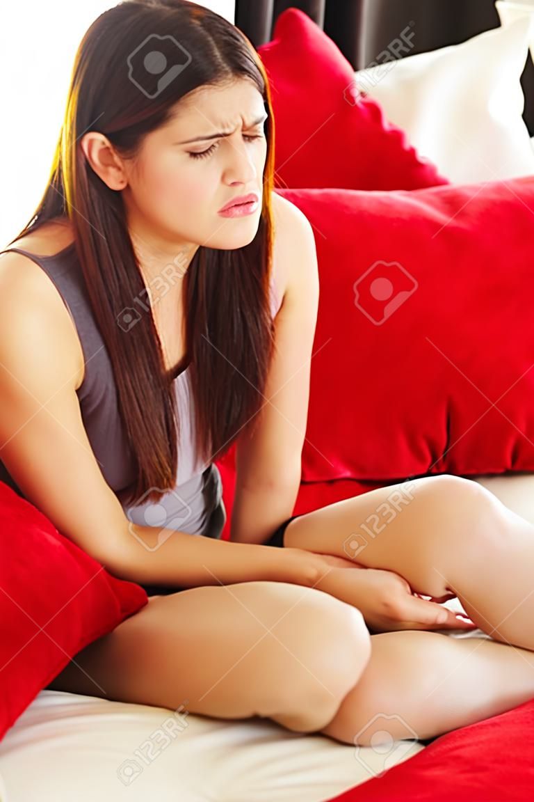 Woman having a stomachache sitting on sofa at her home 