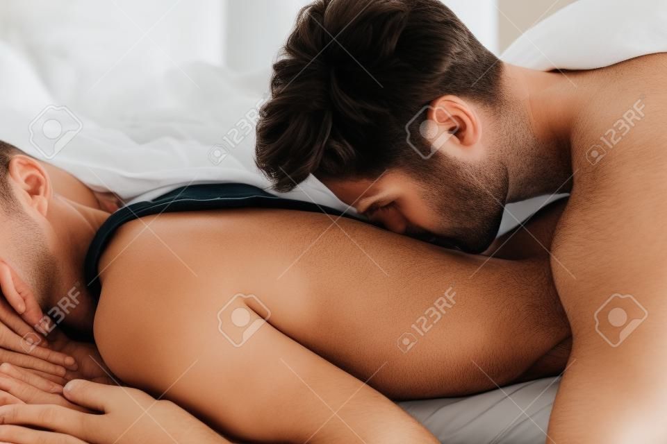 Человек, целовать женщину в спину на кровати.