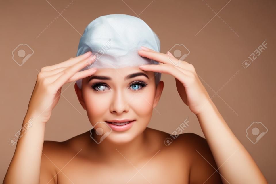 Uma mulher jovem que verifica rugas em sua testa, closeup