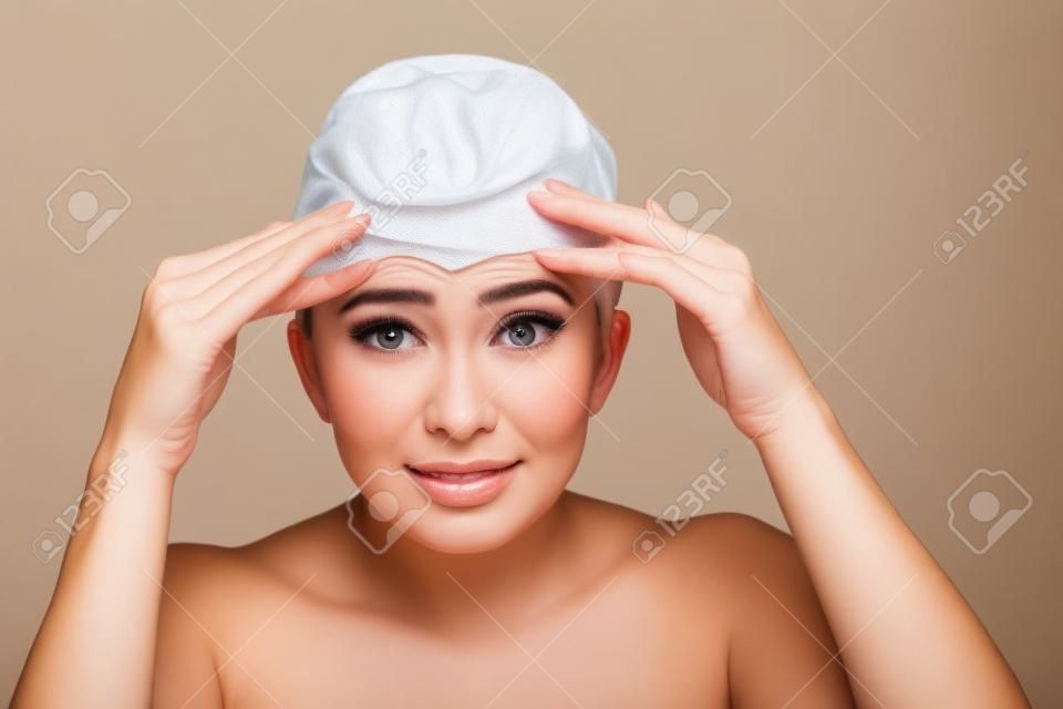 Uma mulher jovem que verifica rugas em sua testa, closeup