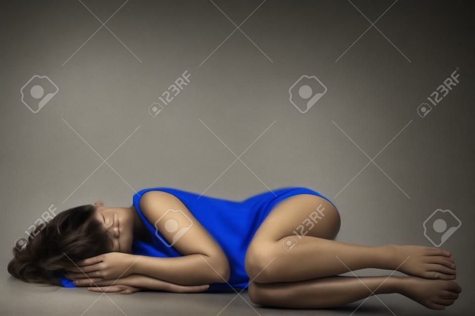 Depressed woman lying on the floor covering her eyes.