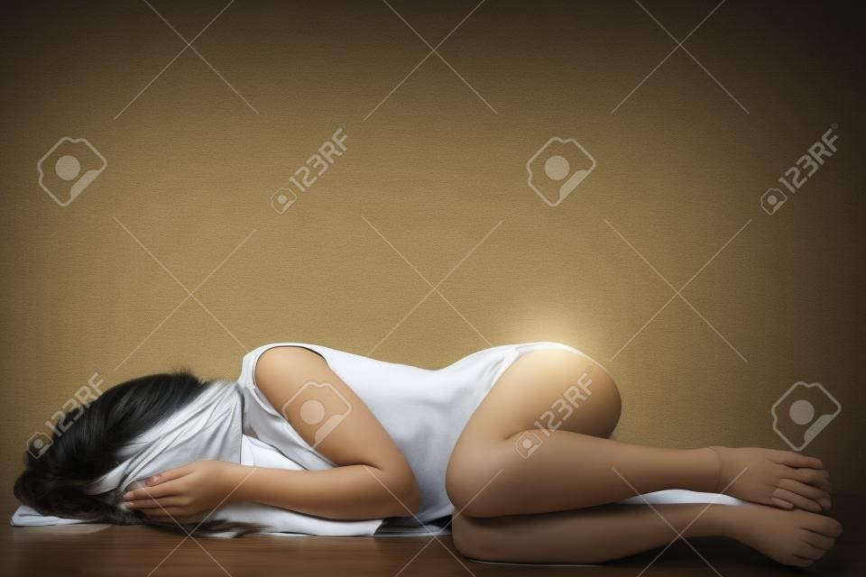Depressed woman lying on the floor covering her eyes.