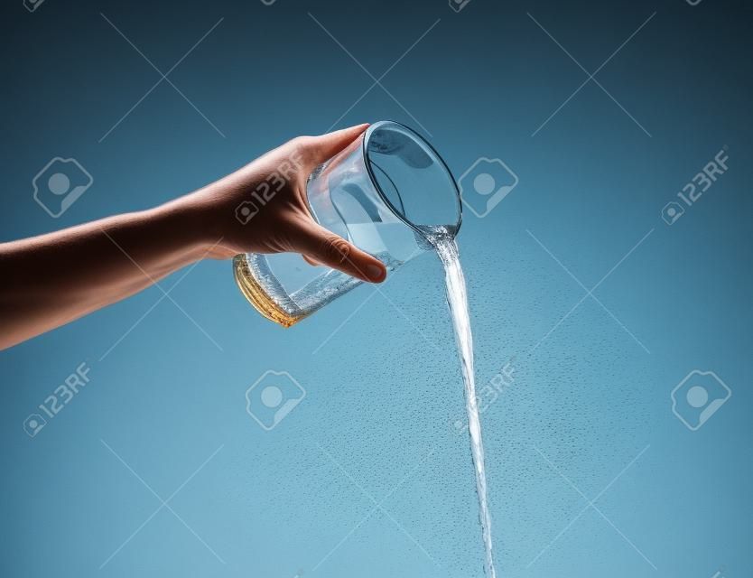 Hand gießt Wasser aus Glas.