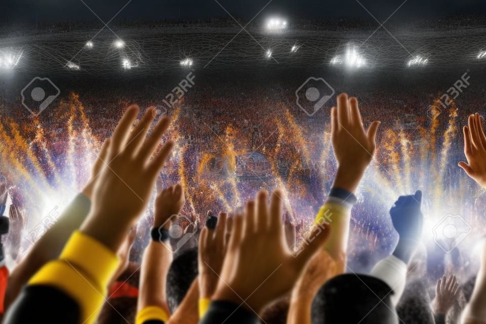 Kibice piłki nożnej wspierają swoją drużynę i świętują bramkę na pełnym stadionie na świeżym powietrzu.