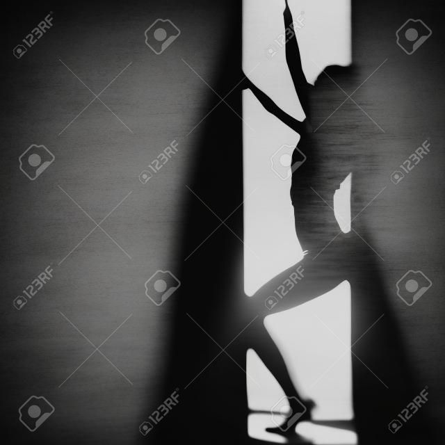 Woman on the background of light, silhouette, black and white photo. Blurred background. Square composition.