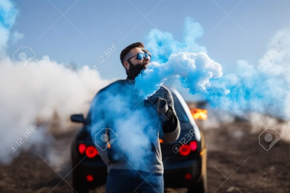 Men with beard vaping outdoor in sunglasses, focus on steam