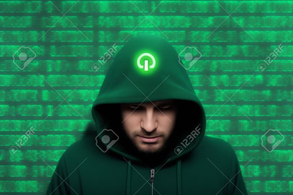 Hacker w zielonym kapturem stoi przed kolorowym tle serwer strumieni binarny cyberbezpieczeństwa koncepcji
