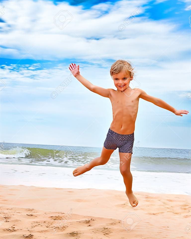 Мальчик прыгает на пляже с видом на море на фоне