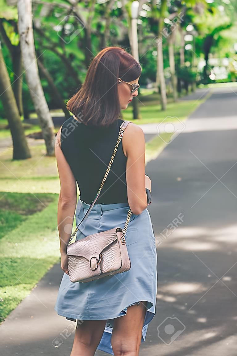 Fashionable woman with luxury snakeskin python handbag outside. Snakeskin fashion concept.