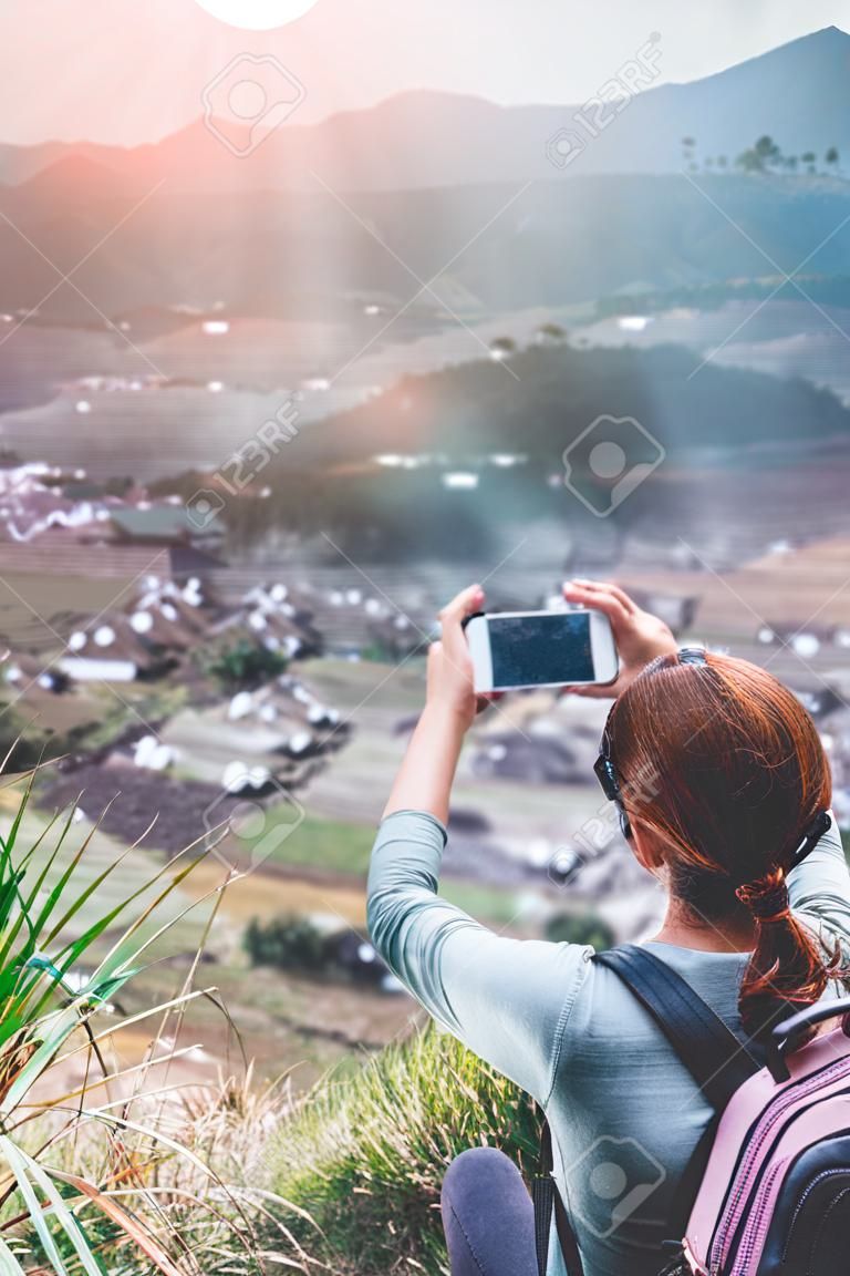 Woman using smartphone on the edge with mountain volcano background. Bali island.