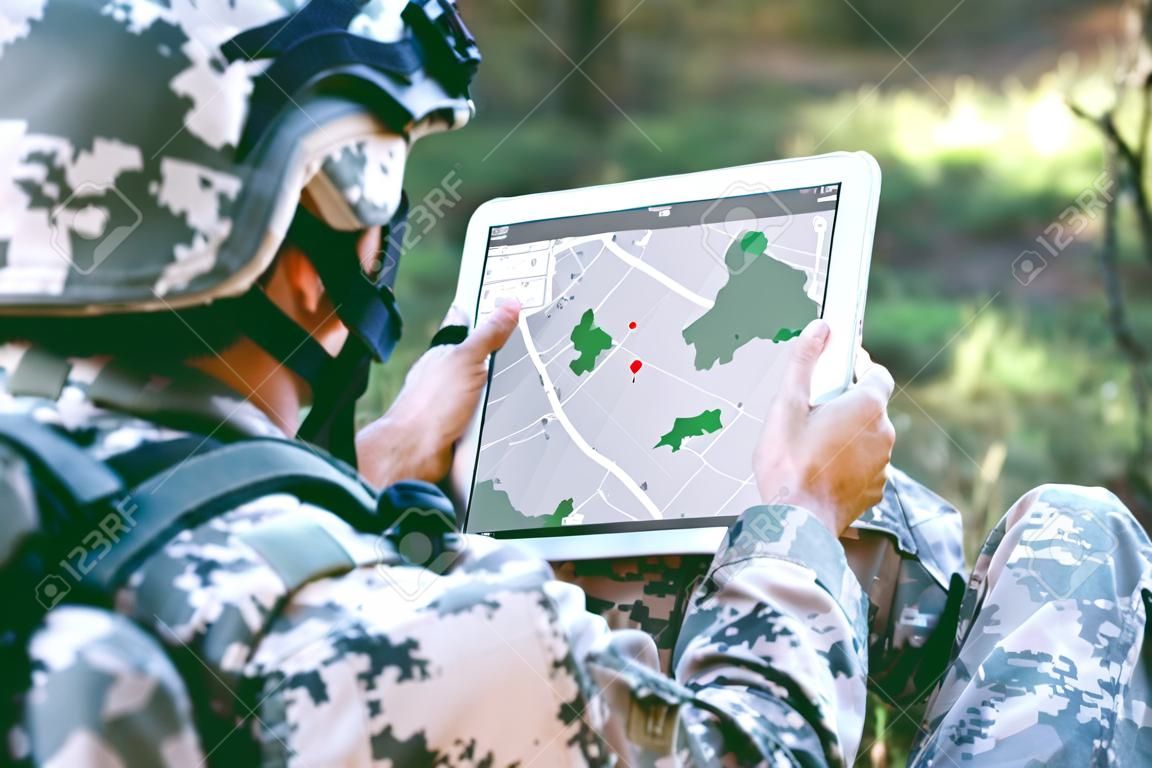Soldado con mapa en tableta para orientación en el bosque