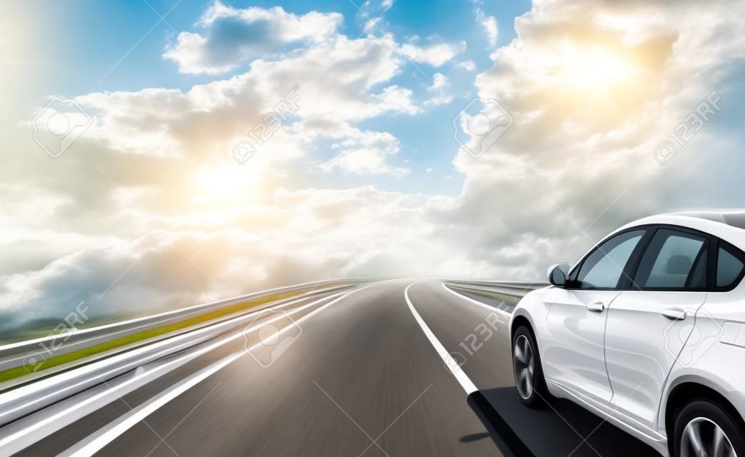 Ein weißes Auto rast auf einer Hochgeschwindigkeitsstraße in der Sonne.