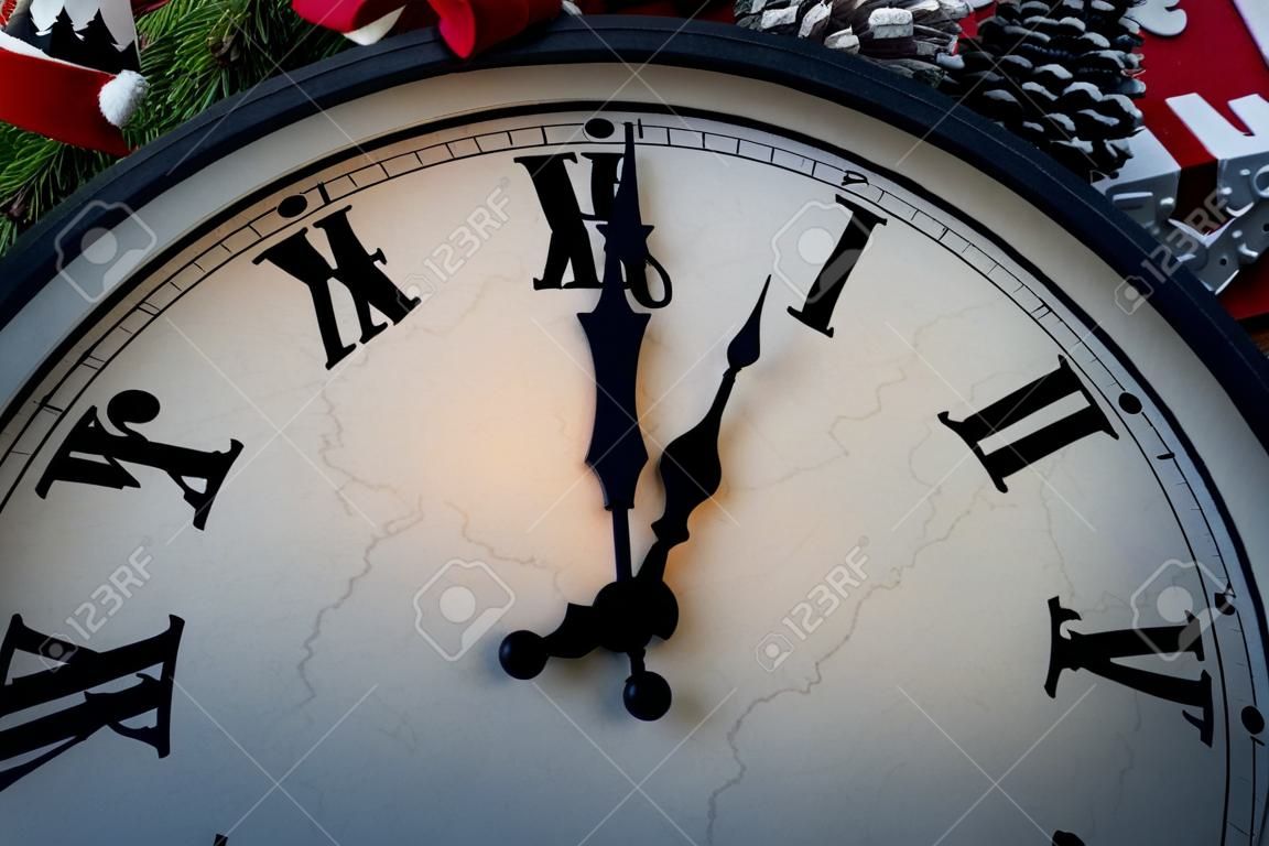 Wall clock in Christmas or New Year decorations are wrapped with fir branches and Christmas decorations. On the clock five minutes to midnight.