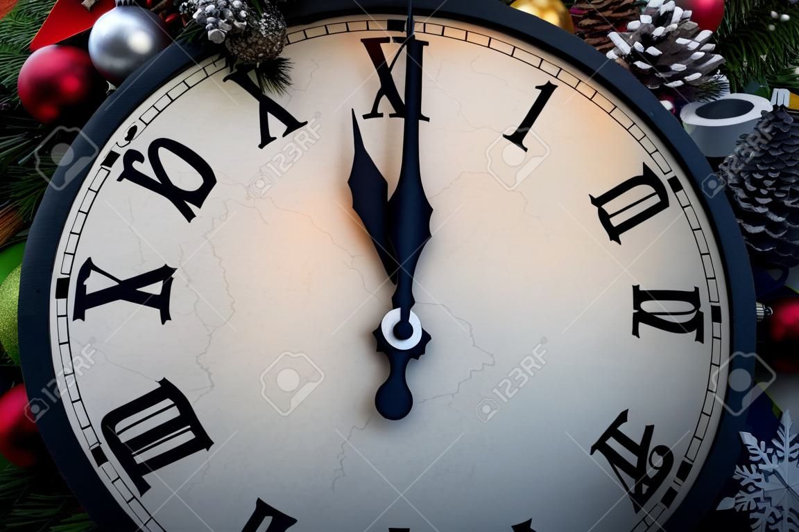 Wall clock in Christmas or New Year decorations are wrapped with fir branches and Christmas decorations. On the clock five minutes to midnight.