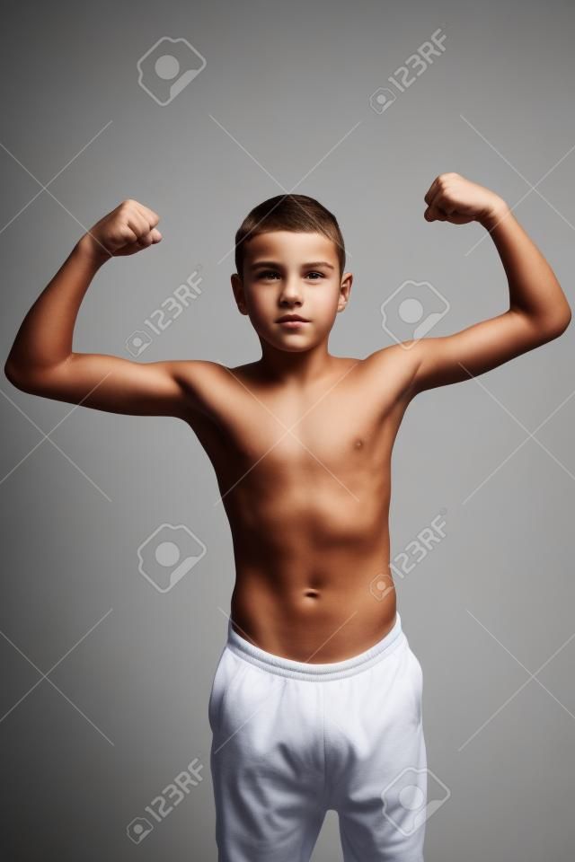 Shirtless teenage boy flexing his muscles isolated on white background