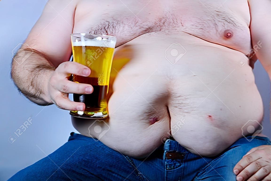 Uomo caucasico senza camicia in sovrappeso che tiene una birra