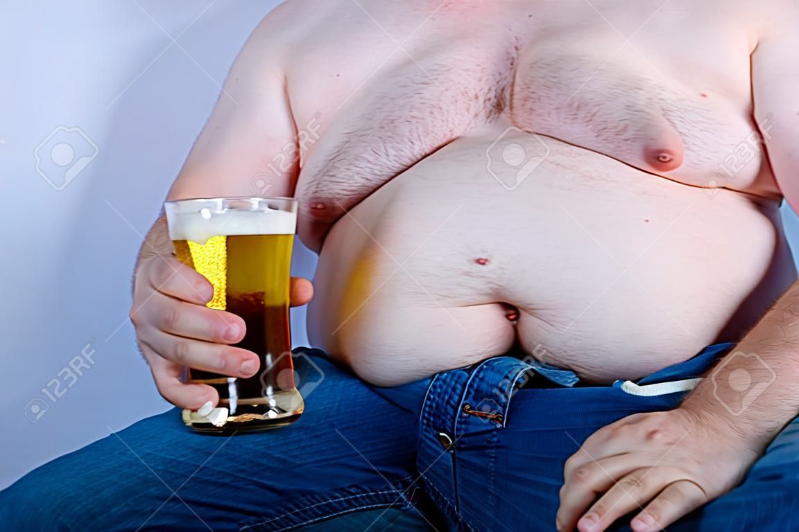 Uomo caucasico senza camicia in sovrappeso che tiene una birra