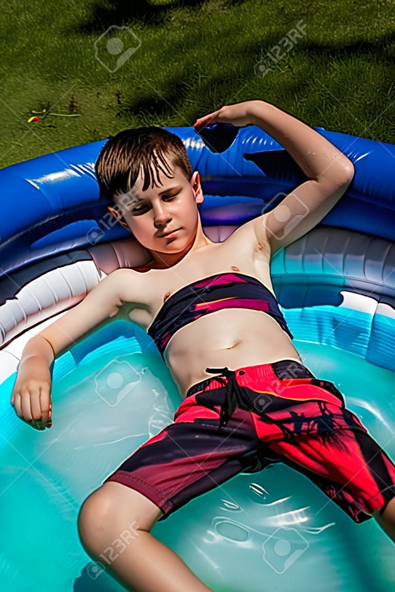 Menino caucasiano sem camisa pré-adolescente deitado em uma piscina de remo