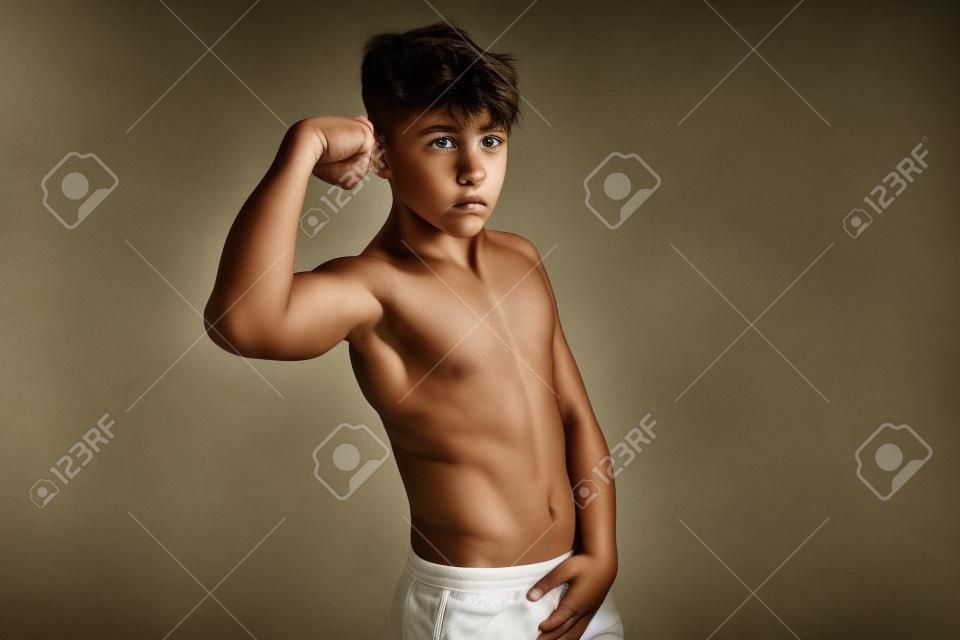 Portrait d'un adolescent torse nu sportif fléchissant ses muscles