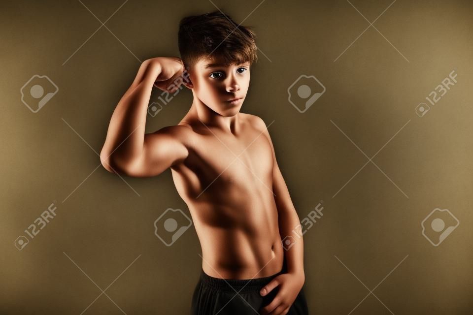 Portrait d'un adolescent torse nu sportif fléchissant ses muscles