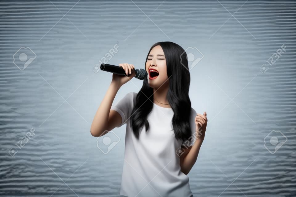 schöne stilvolle Frau singt Karaoke auf weißem Hintergrund.