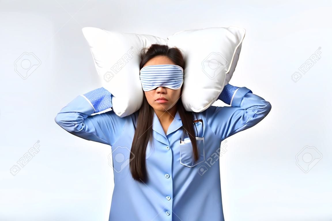 Annoyed and mad grumpy asian girl with insomnia, lying in bed in pajamas and sleeping mask, cover ears with pillow and look bothered, irritated with friend snoring loud at night, white background