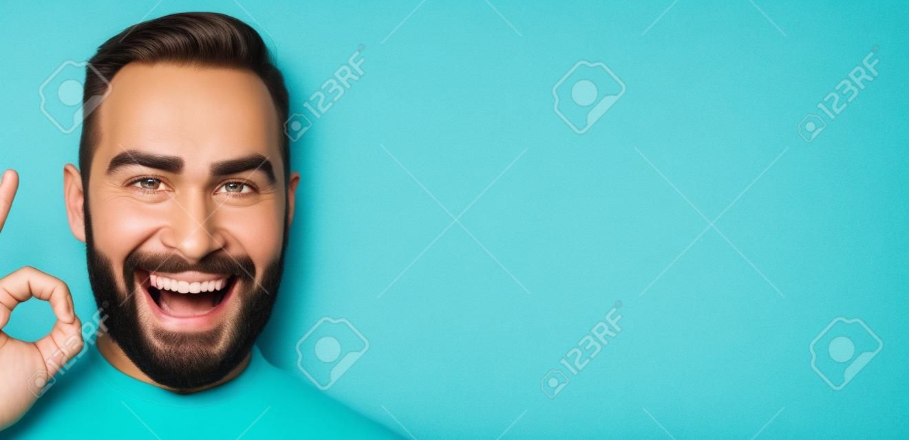Close-up van zelfverzekerde en gelukkige man met baard tonen goed teken, goedkeuren en zoals, het geven van positief antwoord of akkoord, staan over turquoise achtergrond