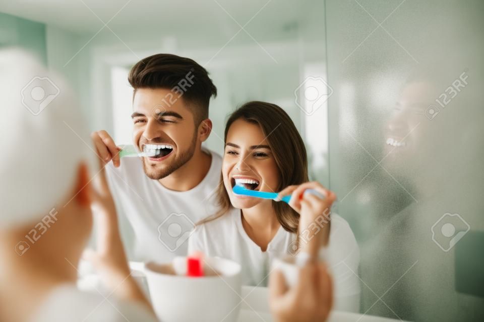 Photo of young couple having fun while brushing teeth in the bathroom.