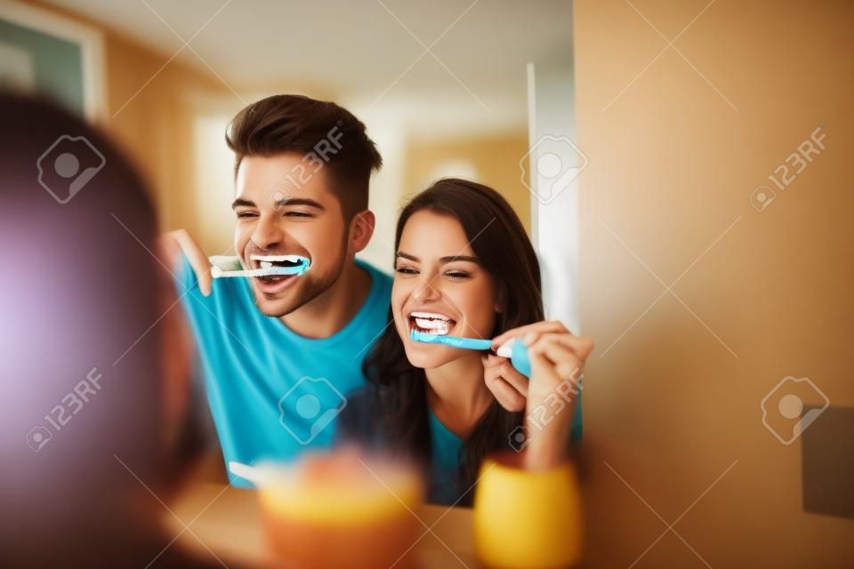 Photo of young couple having fun while brushing teeth in the bathroom.