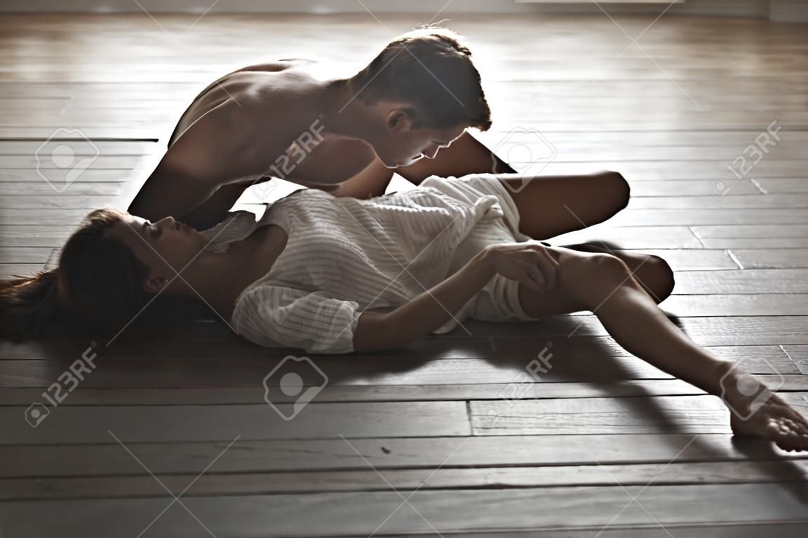 Young passionate lovers lie on the floor and enthusiastically kissing. The boy stuck his fingertips girl under her panties.
