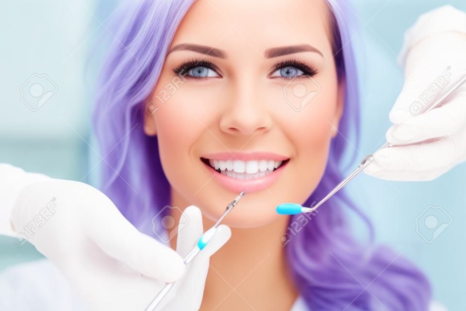Девушка с красивыми белыми зубами на приеме у врача стоматолога.