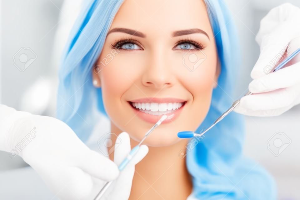 Девушка с красивыми белыми зубами на приеме у врача стоматолога.