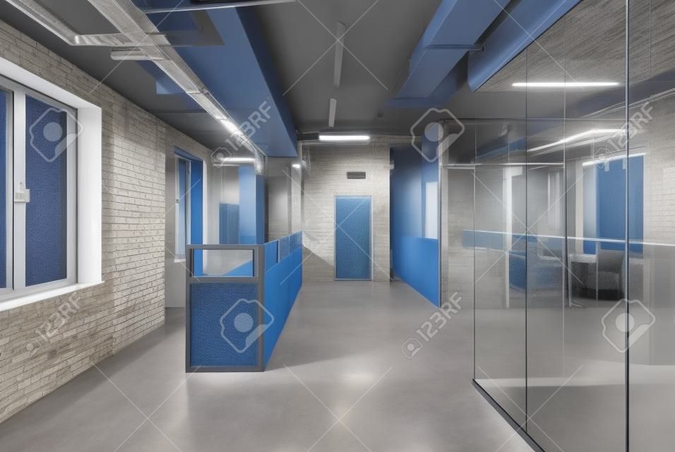 Blue metal reception rack with armchairs in a loft style office with gray walls. There is an entrance door and work zones with glass and mesh partitions. Table with chairs are reflected in the glass.