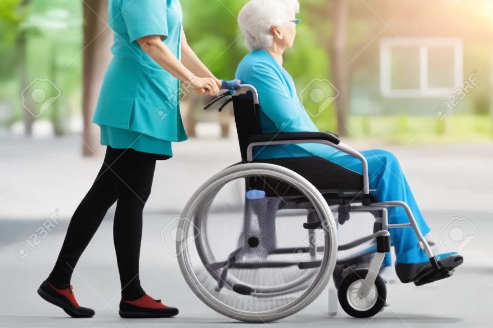 휠체어에 노인 여자와 편안한 산책 간병인