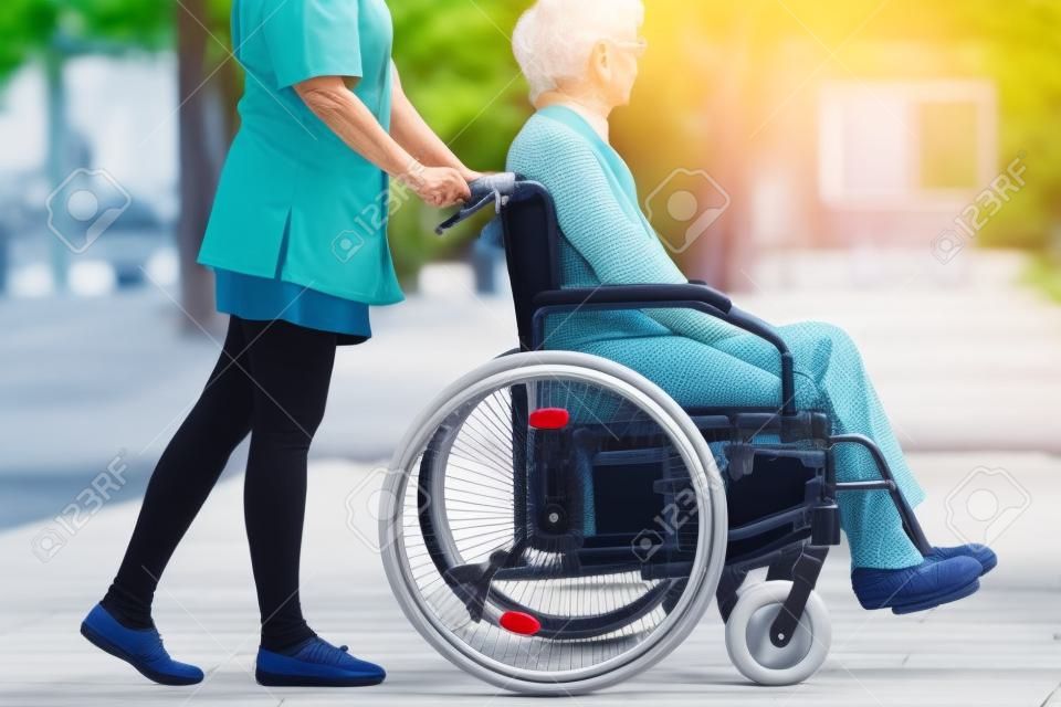 Caregiver su una rilassante passeggiata con la donna anziano sulla sedia a rotelle