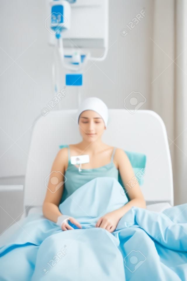 Mujer bonita joven enferma sentado en la cama de hospital
