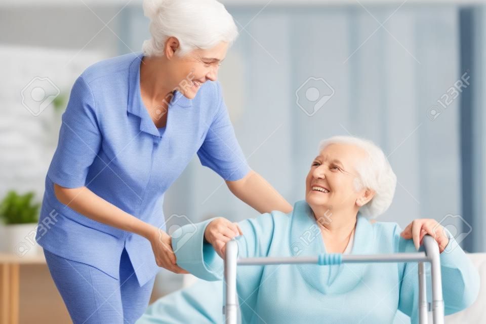Mujer mayor que usa andador y el apoyo a la enfermera