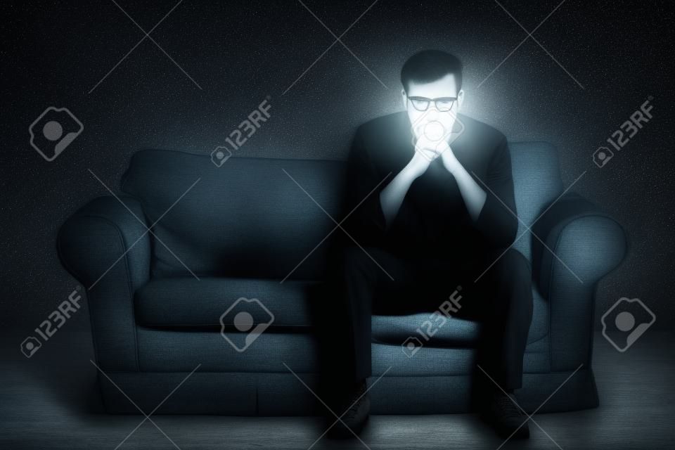 Lonely rozpaczy człowiek siedzi w ciemnym pokoju